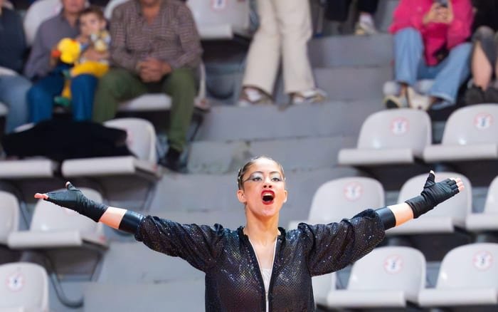 Patinadora con los brazos abiertos y el gesto en tensión durante su ejercicio de competición — foto de Pablo González