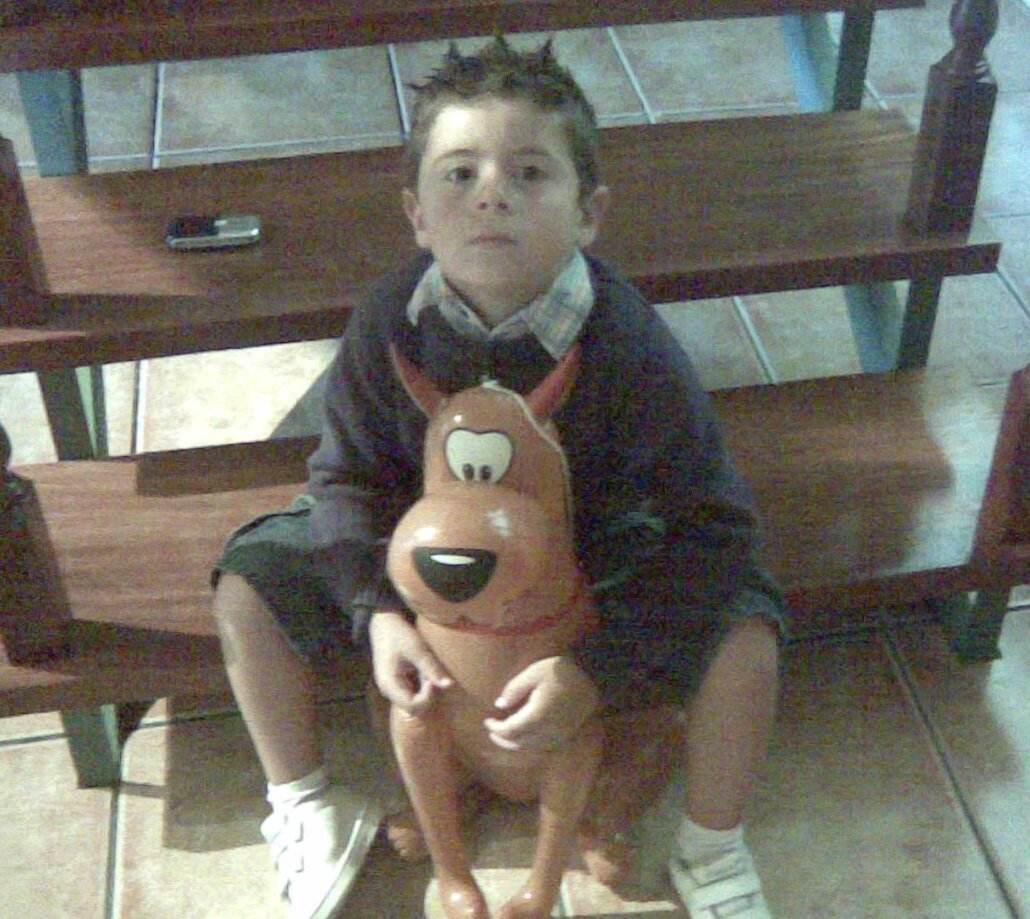 Pablo de niño, sentado en un banco junto a un peluche
